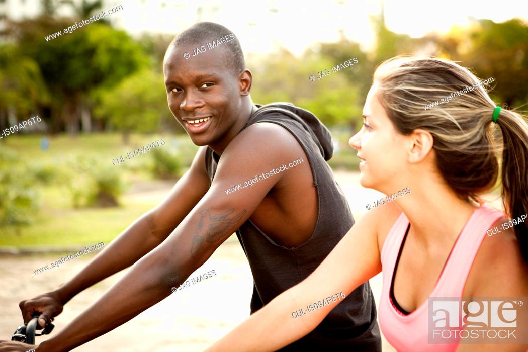 Stock Photo: Young couple preparing to cycle in park.