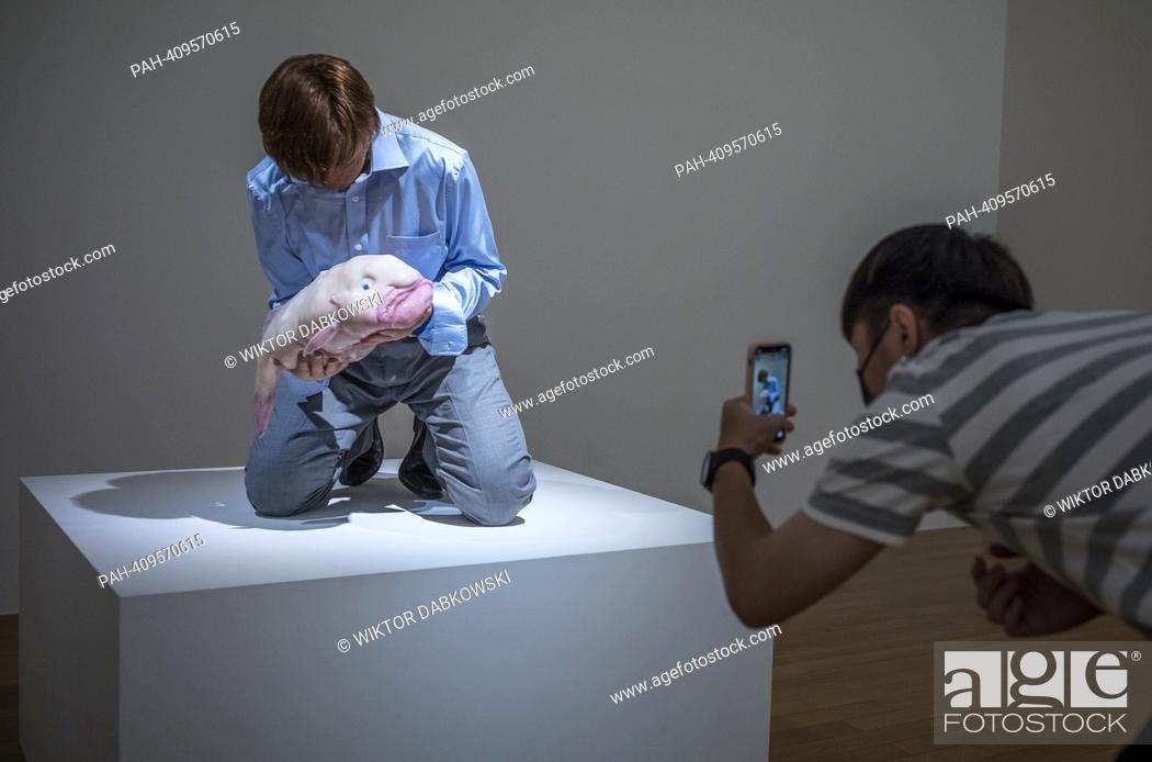 Stock Photo: People look at Eulogy a sculpture of nicely dressed man with blowfish in his hands by Patricia Piccinini during the SUPERNATURAL: Sculptural Visions of the Body.