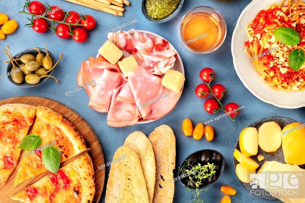 Stock Photo: Italian food. Pizza, pasta, cheese, ham, capers, wine, tomatoes, olives and bread, shot from the top.