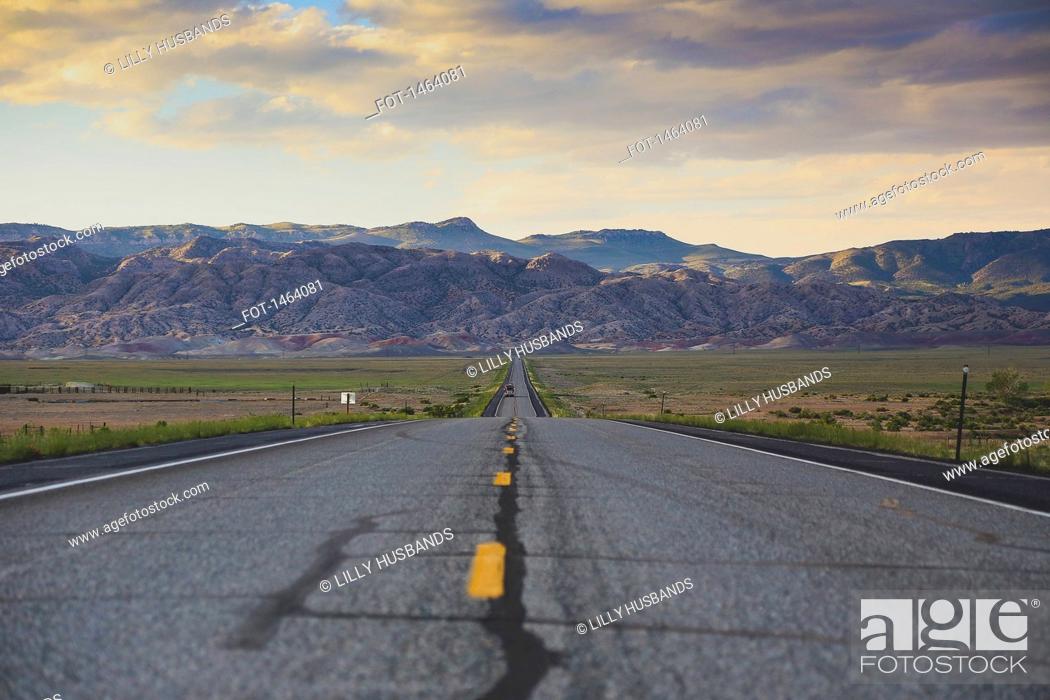 Photo de stock: Road leading towards rocky mountains against cloudy sky.