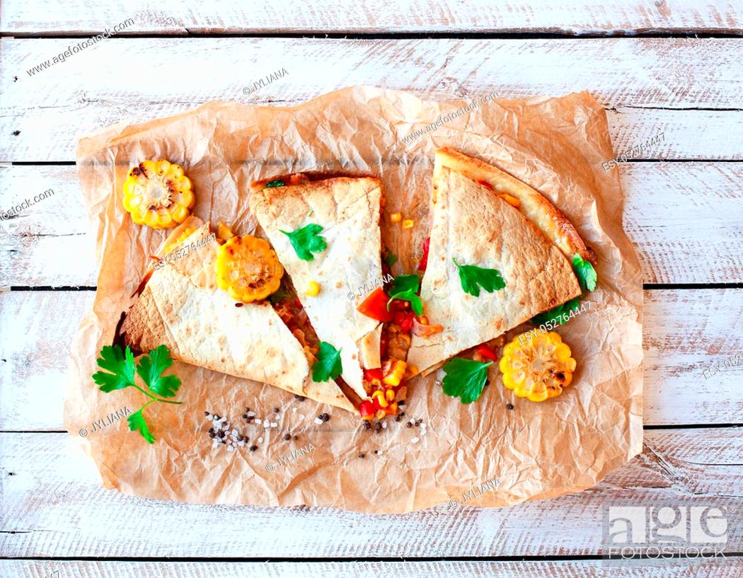 Stock Photo: Mexican Quesadilla wrap with vegetables, corn, sweet pepper and sauces on the parchment and table. horizontal view.