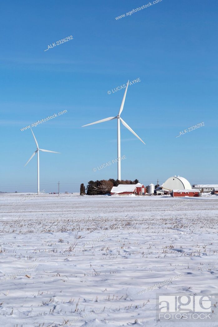 Stock Photo: Wind turbines from the Elk Wind Energy Farm rising above a farm and the snow covered landscape near Greeley in Northeast Iowa, Winter.
