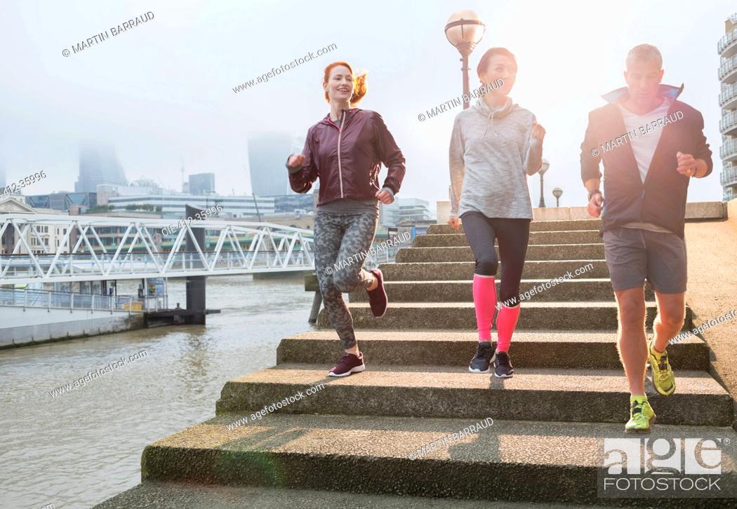Stock Photo: Runners running down steps along sunny urban waterfront.