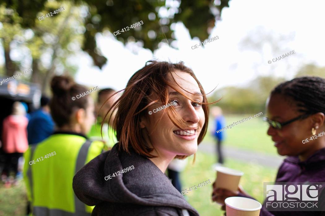 Stock Photo: Portrait smiling female runner resting, drinking water at charity run in park.