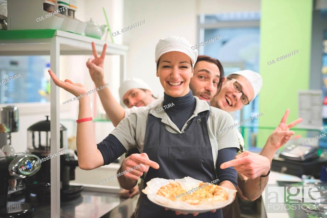 Stock Photo: Waitress carrying plate of food, colleagues making fun behind.