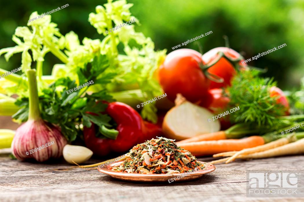 Stock Photo: Plate with pile of dried up and ground vegetables mixed for soup seasoning. Large bunch of various fresh vegetables used as ingredients for seasoning.