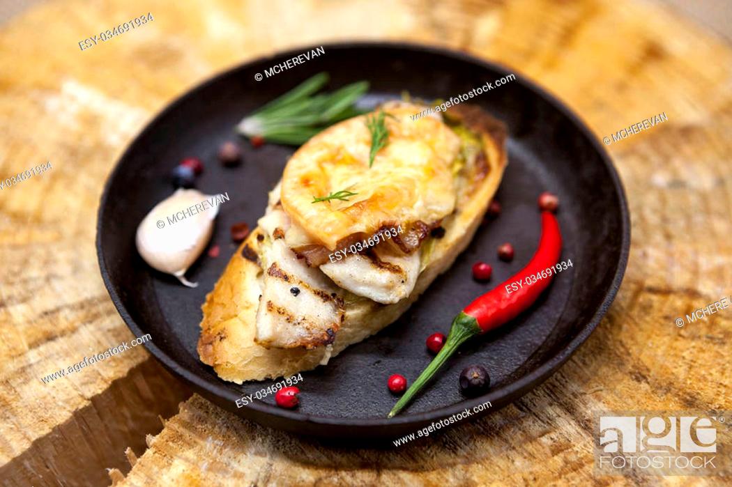 Stock Photo: Home baked hot sandwich with chicken cheese, onion, chile pepper, garlic on a cast-iron pan on a wooden background.