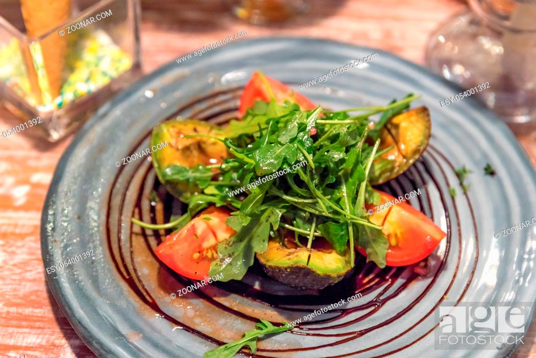 Photo de stock: Grilled avocado salad with tomato and rocket.