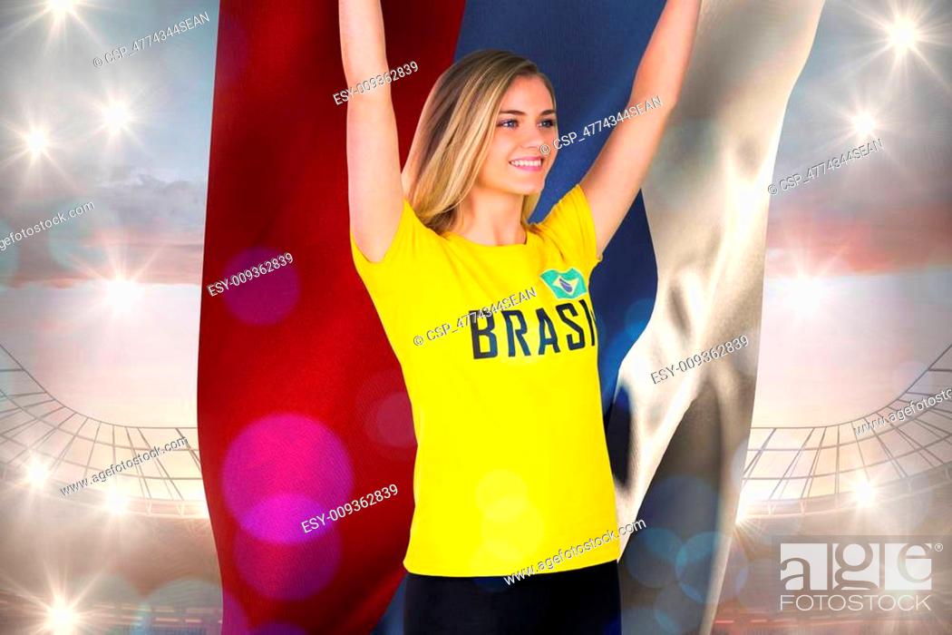 Stock Photo: Excited football fan in brasil tshirt holding russia flag against large football stadium under cloudy blue sky.