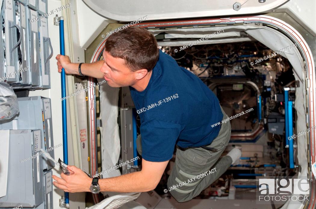 Stock Photo: NASA astronaut Reid Wiseman, Expedition 40 flight engineer, holds a beverage container as he floats through the hatch between the Destiny laboratory and the.