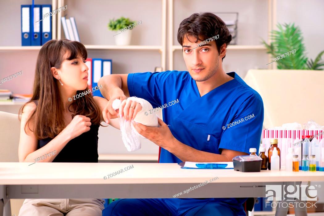 Stock Photo: Young woman with bandaged arm visiting male doctor traumotologist.