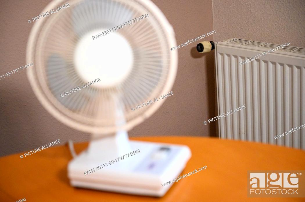 Stock Photo: PRODUCTION - 24 September 2022, Hamburg: A fan stands on the table in an apartment. In the background there is a radiator. Photo: Jonas Walzberg/dpa.