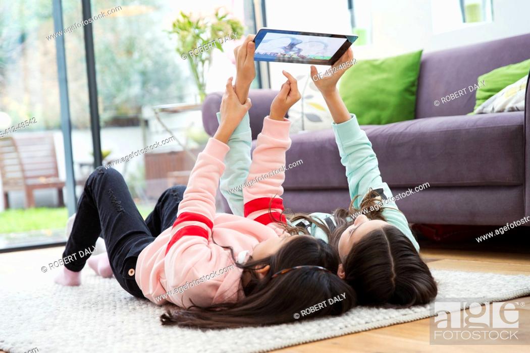 Stock Photo: Girls taking selfie with digital tablet on living room floor.