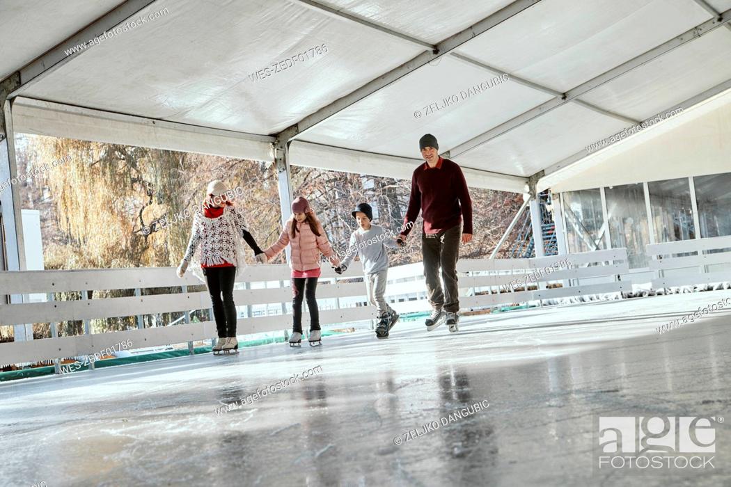 Stock Photo: Family with two kids ice skating on the ice rink.