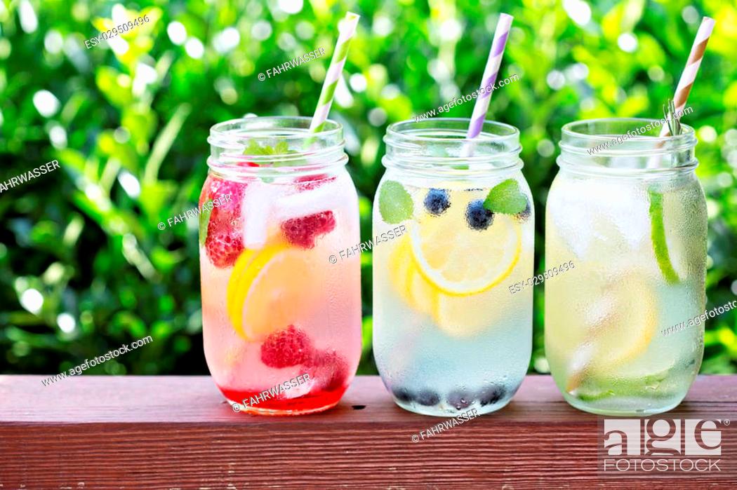 Stock Photo: Variety of lemonade in mason jars with berries and fruits on the front porch.