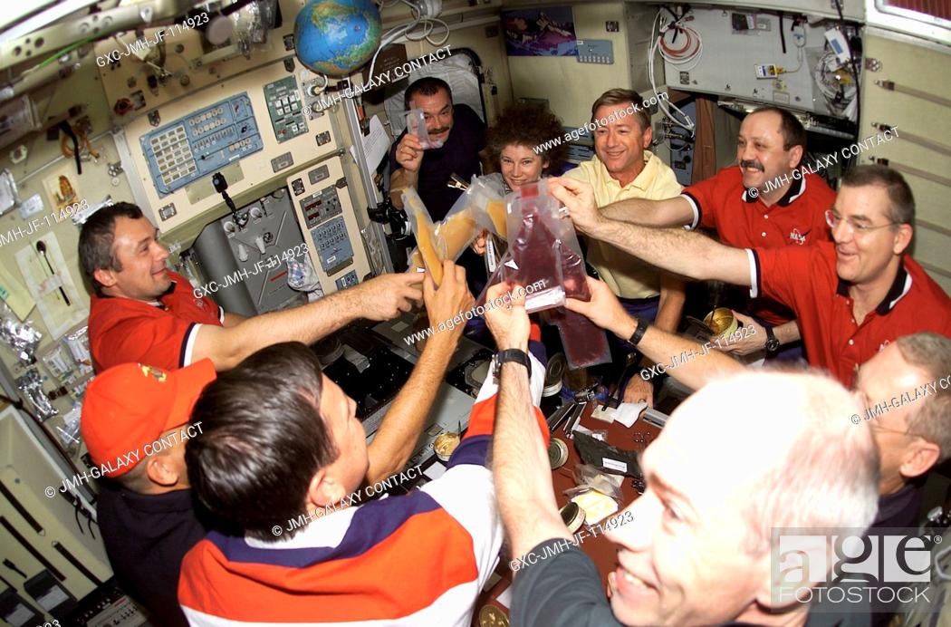 Stock Photo: Beverages are held high in a toast onboard the Zvezda Service Module of the International Space Station (ISS) as the astronauts and cosmonauts of STS-105 and.