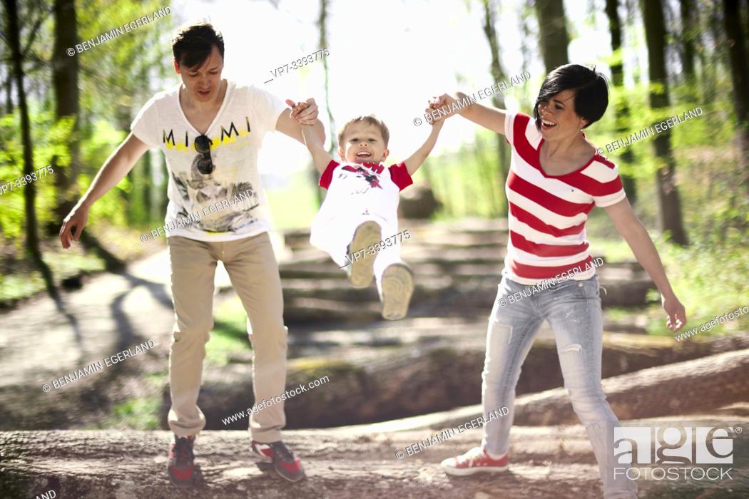 Stock Photo: parents swinging toddler child on hands in forest, at Herrenchiemsee, Chiemsee, Bavaria, Germany.