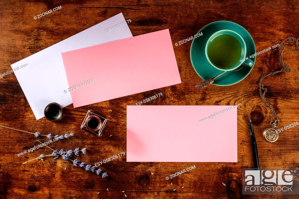 Stock Photo: Pink mockup for an invitation or greeting card, shot from above on a dark rustic wooden background with lavender and green tea.