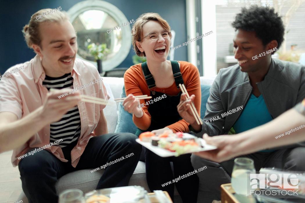 Stock Photo: Happy friends sharing sushi in living room.