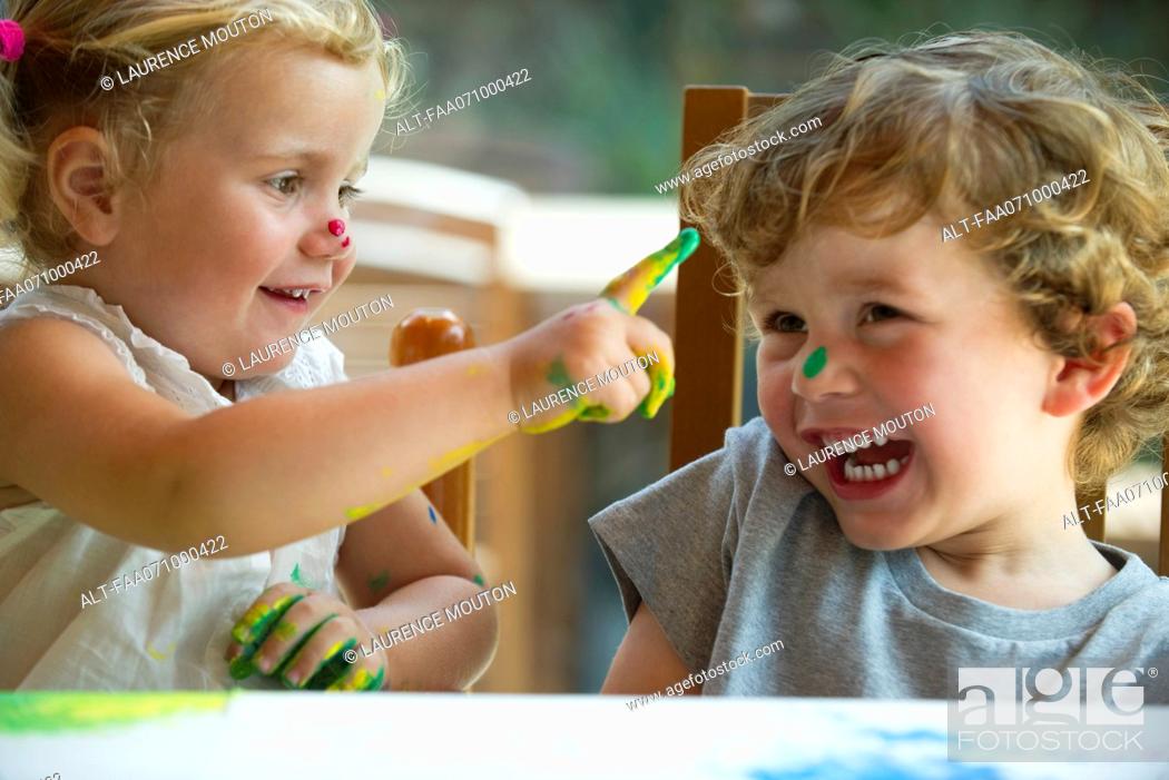Photo de stock: Little girl wiping paint on her brother's nose.