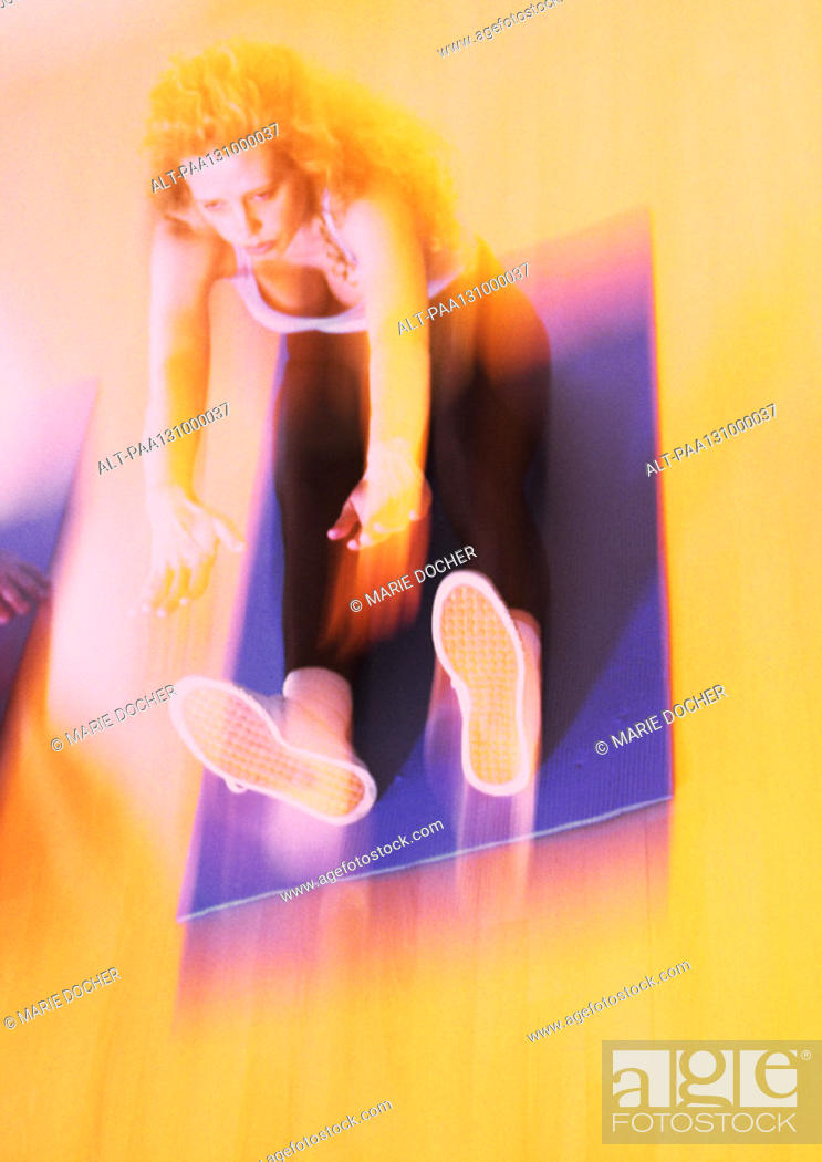 Stock Photo: Woman stretching on mat, blurred.