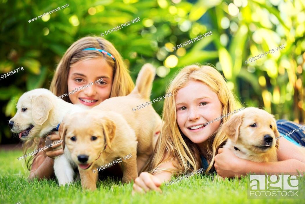 Stock Photo: Adorable Cute Young Girls Playing and Hugging Puppies.