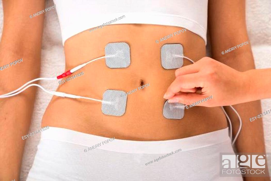 Stock Photo: High Angle View Of Therapist Placing Electrodes On Woman's Stomach.
