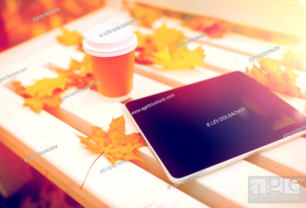 Stock Photo: season, technology and advertisement concept - tablet pc computer and coffee paper cup on bench in autumn park.