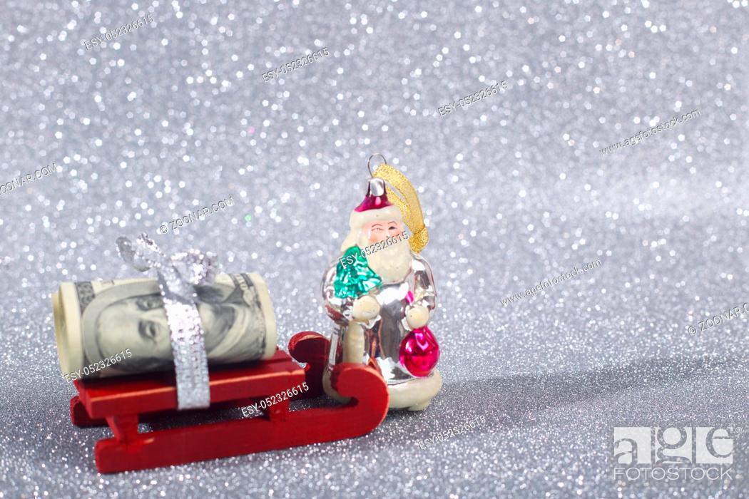 Stock Photo: Santa Claus brings money on his sledge on glitter background.