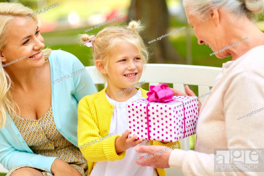 Stock Photo: happy family giving present to grandmother at park.