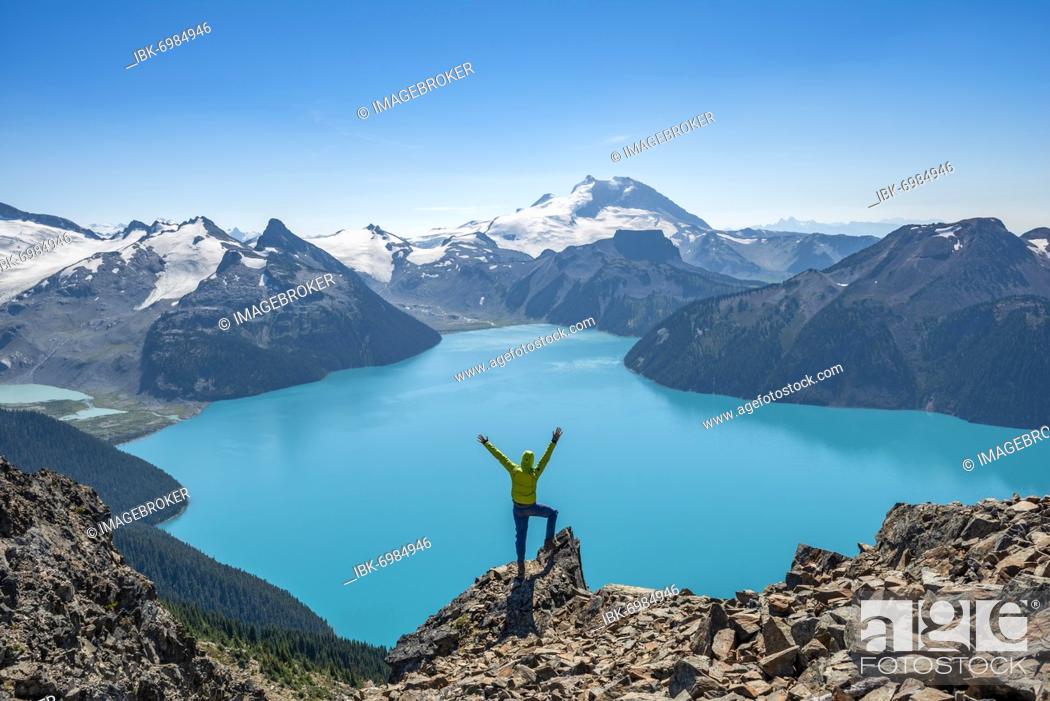 Stock Photo: Young man standing on a rock, looking into the distance, view of mountains and glacier with turquoise blue lake Garibaldi Lake, peaks Panorama Ridge.