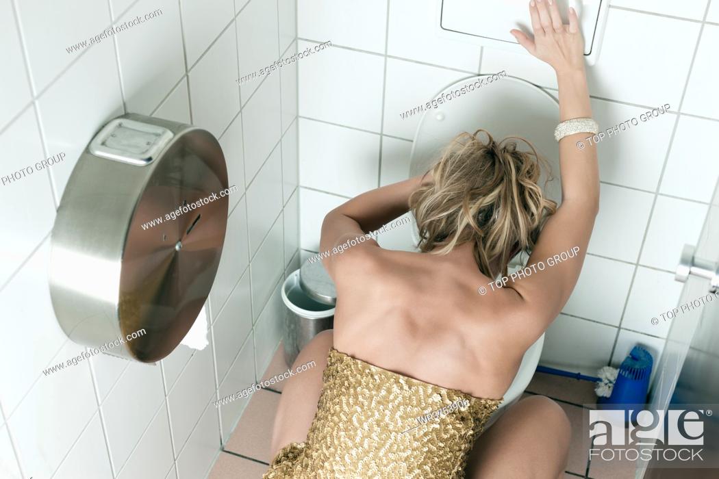Stock Photo: Woman had too many drinks and is drunk and is throwing up in the toilet.