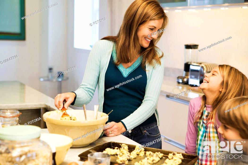 Stock Photo: A Woman and Two Children Laughing and Making Cookies in the Kitchen.
