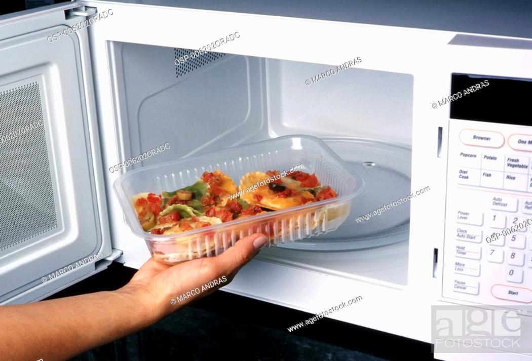 a person putting food inside the microwave, Stock Photo, Picture And