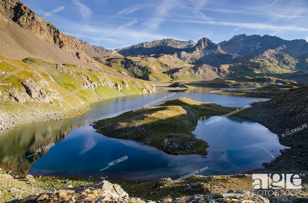 Stock Photo: The calm surface of an alpine lake, under rocky ridges, in the early morning in summertime. (Valsavarenche, Aosta Valley, Italy).