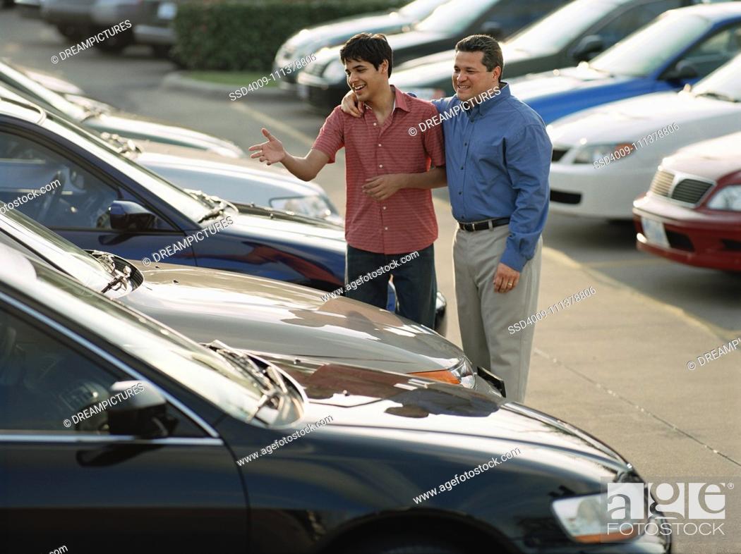Stock Photo: Car salesman and customer picking out a car.