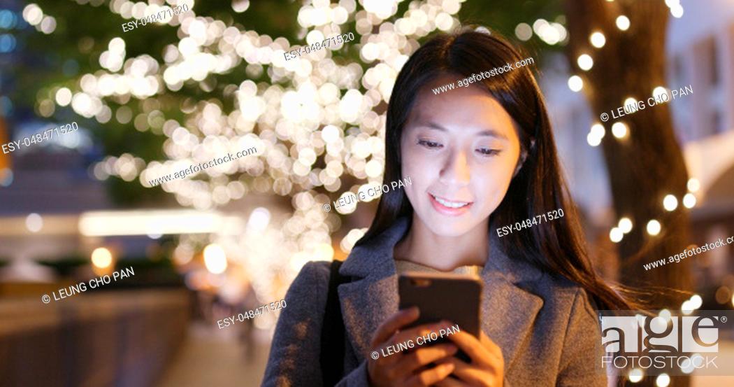 Stock Photo: Young businesswoman use of mobile phone in city with christmas decoration.
