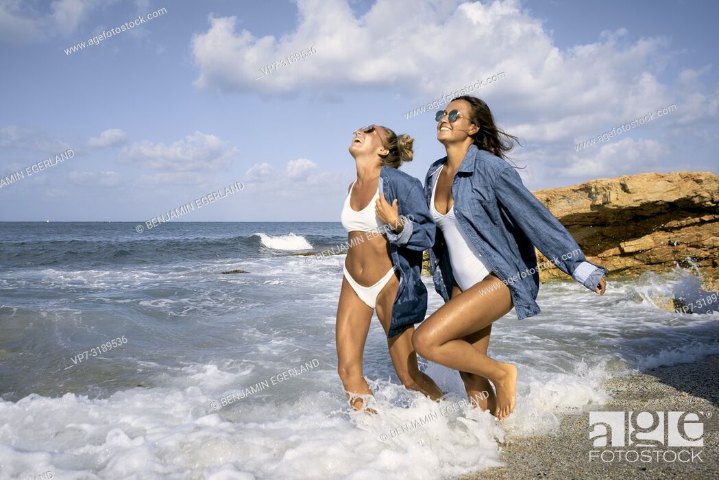 Stock Photo: Two women running in sea water at beach, Chersonissos, Crete, Greece.