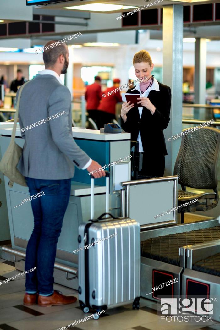 Stock Photo: Commuter standing at counter while attendant checking his passport.