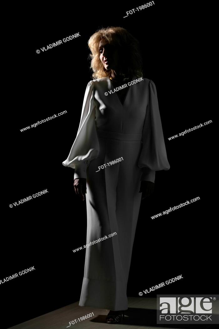 Stock Photo: Portrait woman in white against black background.