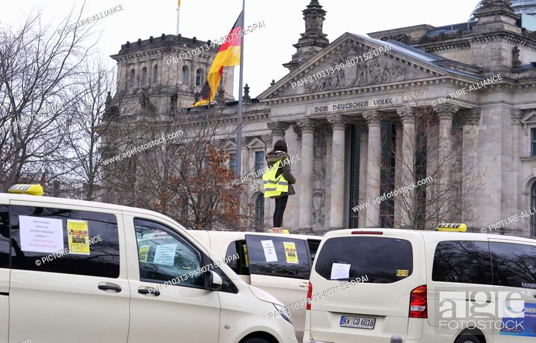 Stock Photo: 13 March 2021, Berlin: A young woman stands on the roof of a taxi during a demonstration in front of the Reichstag by Berlin taxi drivers against the planned.