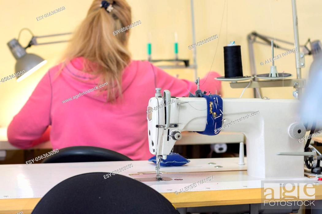 Stock Photo: Girl sits with her back and sews on a sewing machine in a sewing shop.