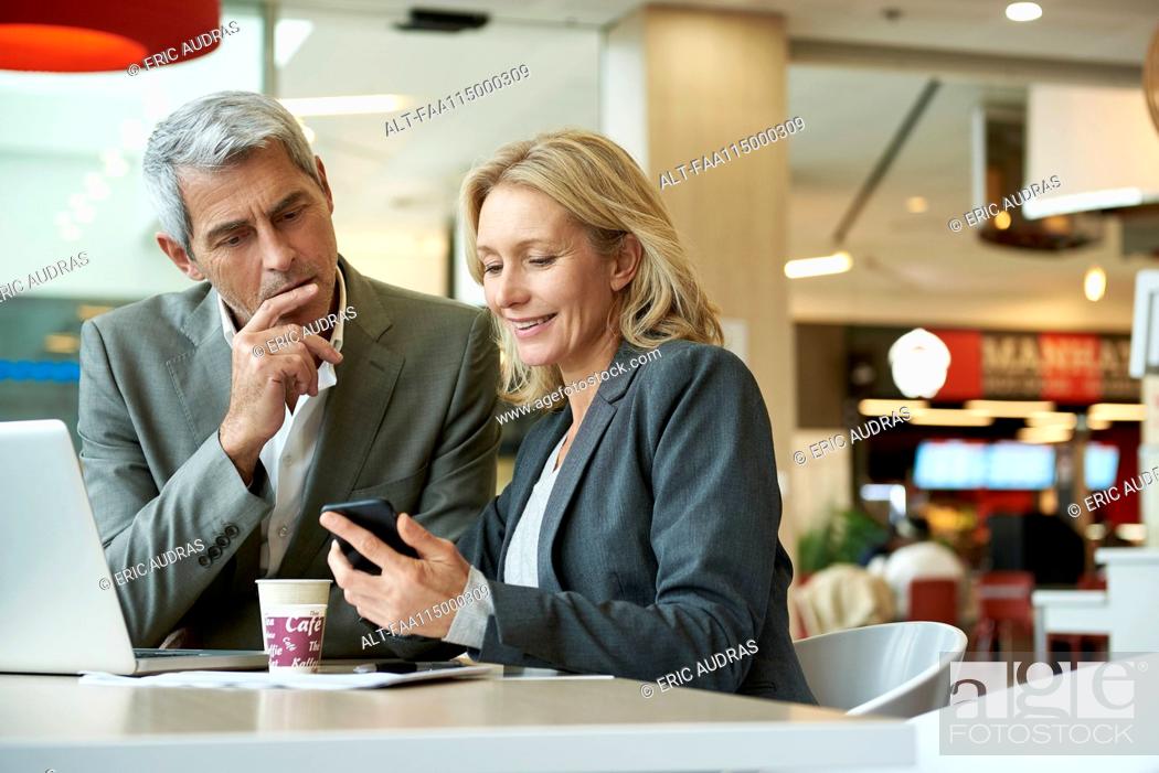 Stock Photo: Businesspeople using smart phone in cafeteria.