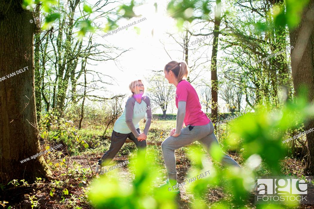 Stock Photo: Women face to face in forest hands on knee lunging.