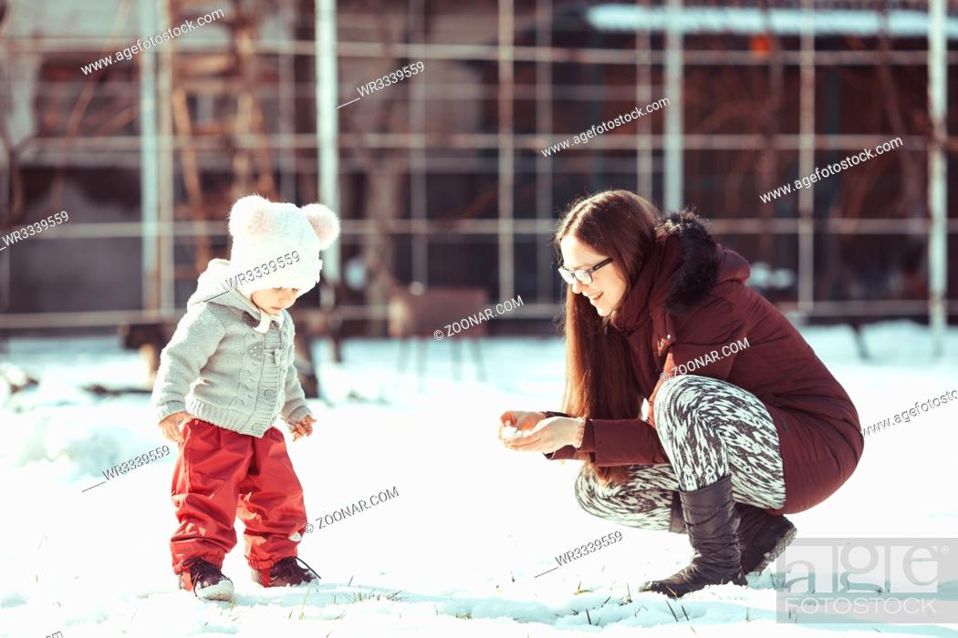 Photo de stock: Mom shows the snow to a little girl at the cold sunny winter day.
