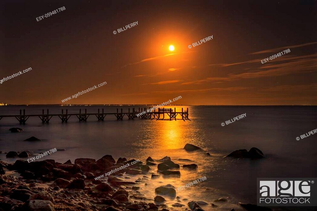 Stock Photo: Moon Rising Night Stars Beach Pier Buzzards Bay Ocean Padanaram Dartmouth Massachusetts New Bedford Lights in distance.