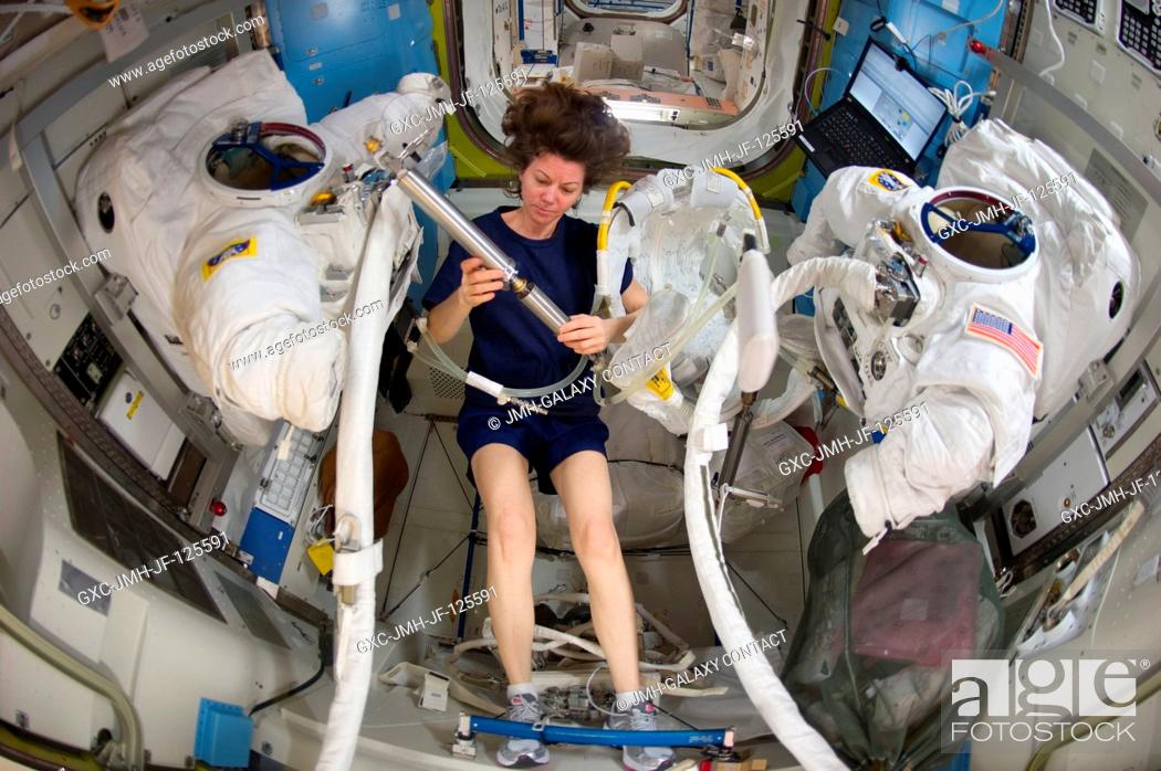 Stock Photo: NASA astronaut Catherine (Cady) Coleman, Expedition 26 flight engineer, works with Extravehicular Mobility Unit (EMU) spacesuit equipment in the Quest airlock.