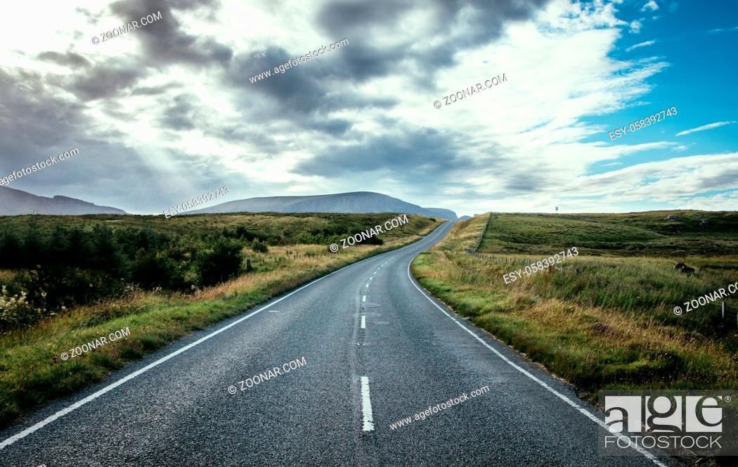 Stock Photo: Asphalted, dramatic road in Scotland. Nobody and cloudy sky.