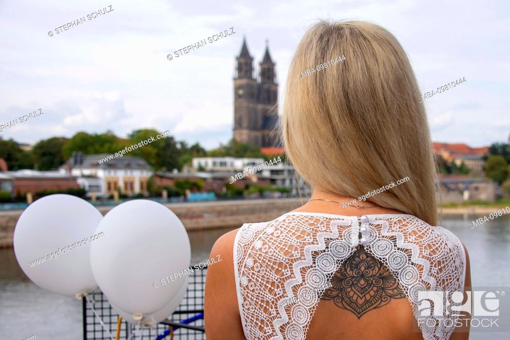 Imagen: Young woman, blonde hair, looks at a diner en blanc on the cathedral in Magdeburg, wearing a tattoo on the back.