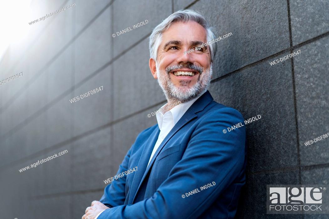Stock Photo: Portrait of smiling mature businessman at a wall.